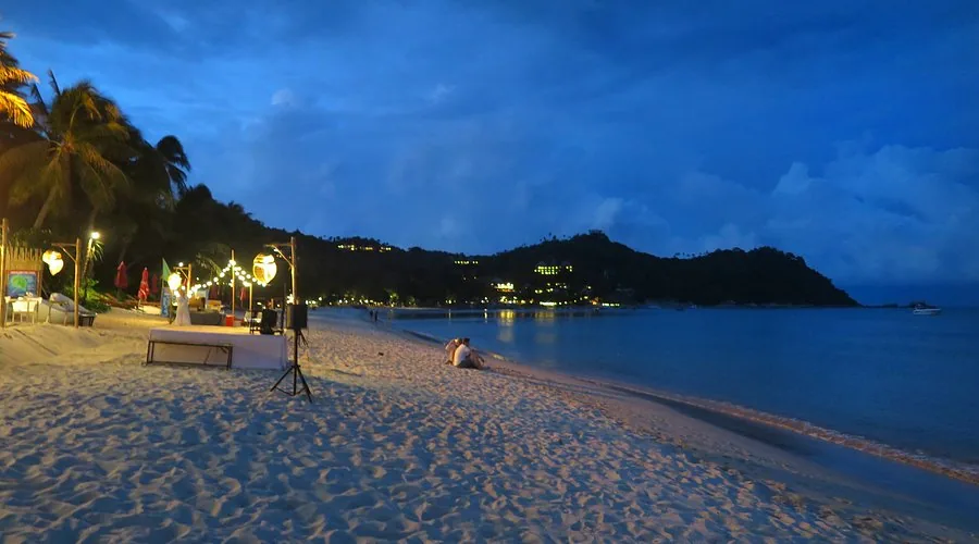 Thong Nai Pan beach at night — couple on the sand, string lights, Koh Phangan
